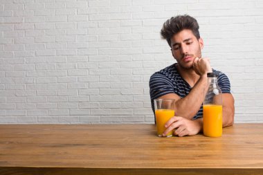 Bir tablo şüphe ve karışık, düşünme, bir fikir ya da bir şey hakkında endişe üzerine oturan genç yakışıklı ve doğal adam. Bir kahvaltı yapıyor, portakal suyu ve tahıl bowl içerir.