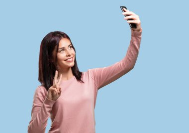 Genç bir selfie alarak, cep komik ve kaygısız bir jest ile seyir, sosyal ağlar ve Internet sörf kadın kendinden emin ve neşeli, tatlı