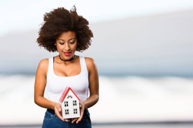 bir küçük ev modeli üzerinde arka plan bulanık tutan genç siyah kadın