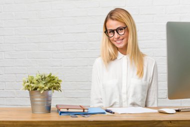 Neşeli ve büyük bir gülümseme ile kendinden emin, samimi ve içten, görevleri yapmak masasına oturan genç öğrenci portresi pozitifliği ve başarı ifade etmek