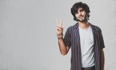 Genç yakışıklı adam eğlenceli ve mutlu, pozitif ve doğal, zafer, barış kavramı bir jest yapar
