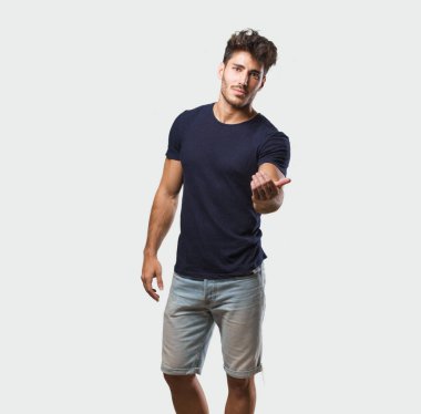 Genç yakışıklı adam ayakta, kendine güvenen gelmek için davet ve gülümseyen bir jest pozitif ve güler yüzlü olmak el ile yapma