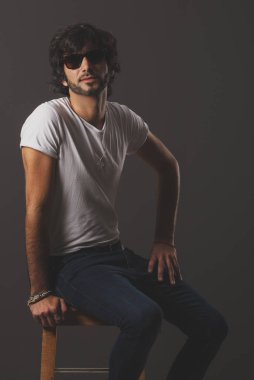 Genç yakışıklı adam neşeli ve kendine güvenen Studio kamera bakıyor 