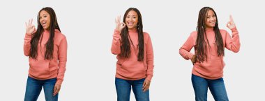 Fitness genç siyah kadın neşeli ve kendine güvenen gri arka plan üzerinde ok jest yapıyor kümesi