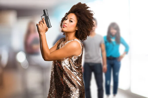 背景のぼけの人々 と銃を使用して若い黒人女性 — ストック写真