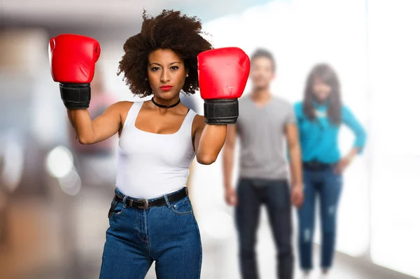 young black woman using boxing gloves with blurred people in background