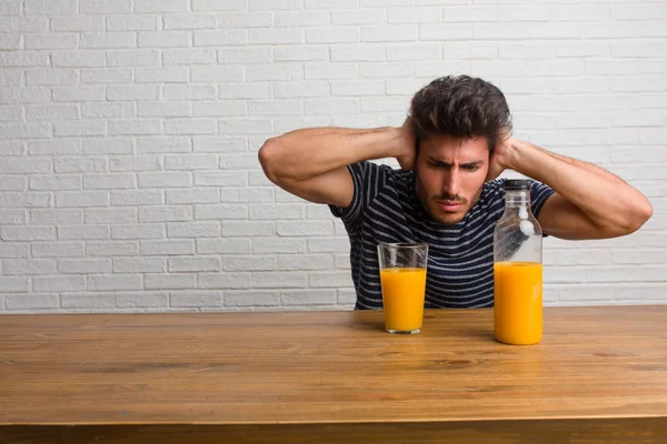 Joven Hombre Guapo Natural Sentado Una Mesa Cubriendo Las Orejas — Foto de Stock