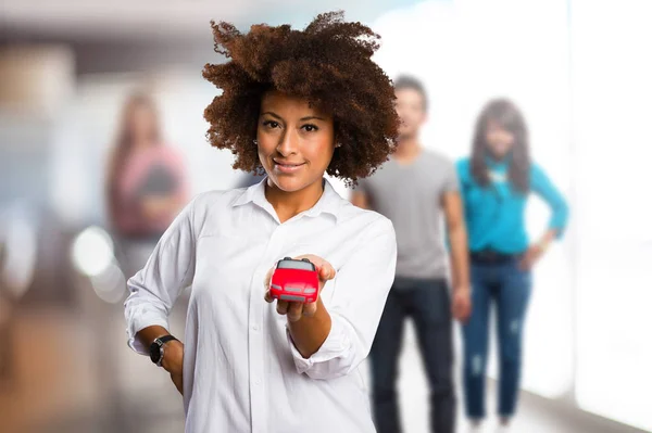 年轻的黑人妇女持有一辆红色的车在背景模糊的人 — 图库照片