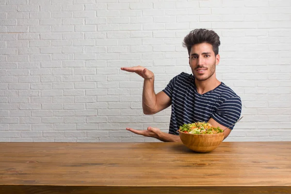 Joven Hombre Guapo Natural Sentado Una Mesa Sosteniendo Algo Con — Foto de Stock