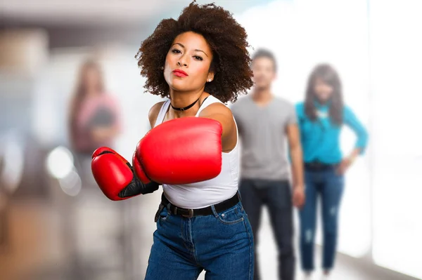 young black woman using boxing gloves with blurred people in background