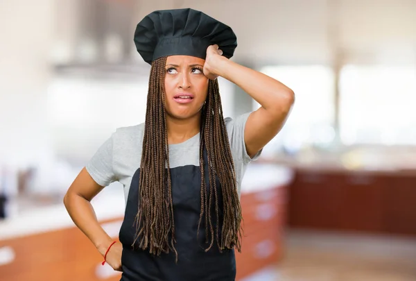 Portrait of a young black baker woman worried and overwhelmed, forgetful, realize something, expression of shock at having made a mistake