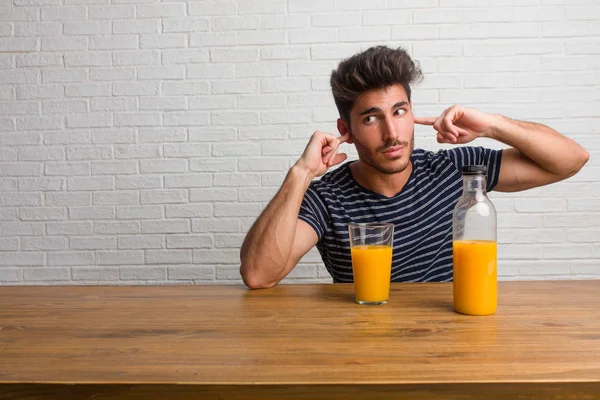 Joven Hombre Guapo Natural Sentado Una Mesa Cubriendo Las Orejas — Foto de Stock