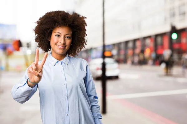 young black woman doing victory gesture on blurred background