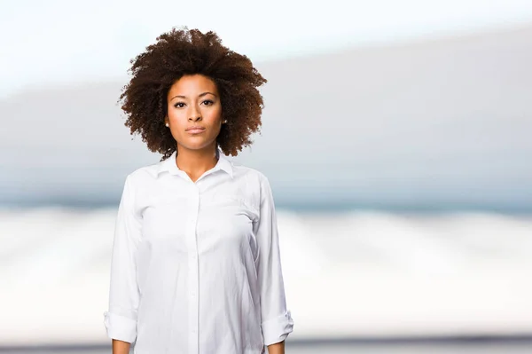 young black woman in white shirt standing on blurred background