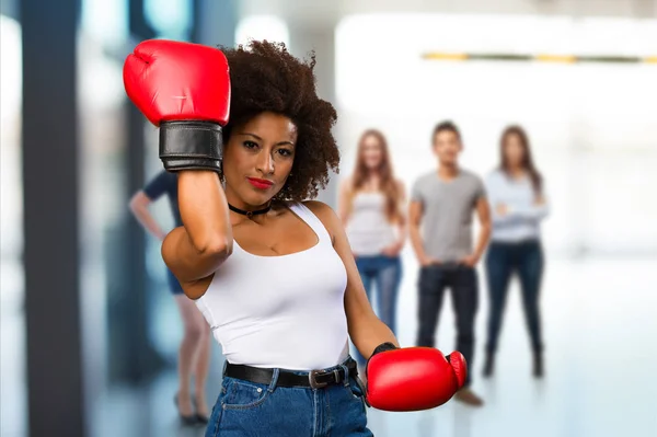 young black woman using boxing gloves with blurred people in background