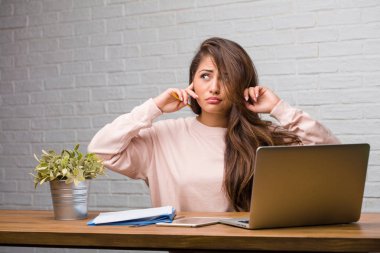 Eller, kızgın ve bazı ses işitme yorgun kulaklarıyla kapsayan masasına oturan genç öğrenci latin kadın portresi