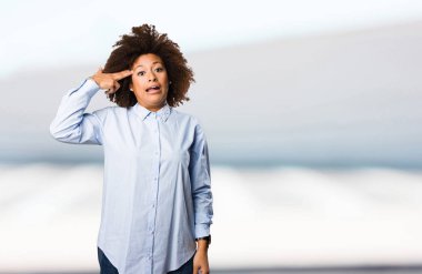 Genç siyah kadının arka plan bulanık silah jest yapması