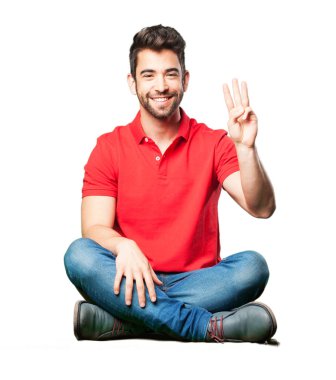 Beyaz arka plan üzerinde izole sayı üç jest yapıyor oturan adam