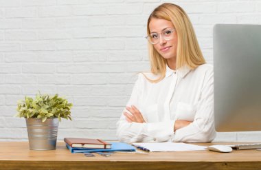 Kollarını, gülümseyen ve mutlu crossing, kendinden emin ve dostça görevleri yapmak onun masasına oturan genç öğrenci portresi