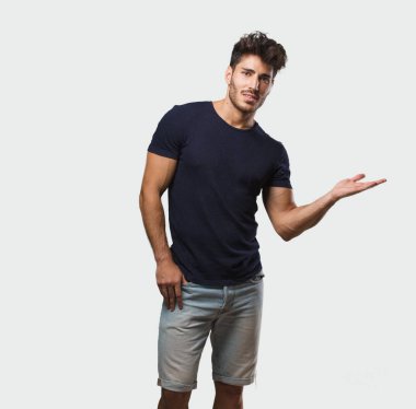 Genç yakışıklı ayakta el ile bir şey tutan adam bir ürün, gülümseyen ve neşeli gösterilen, hayali bir nesne sunan