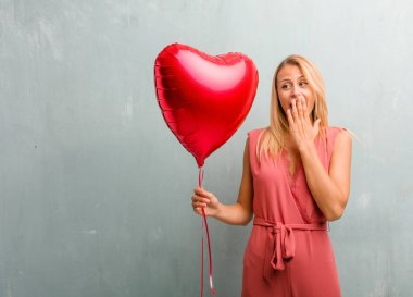 Zarif sarışın genç kadın bir kırmızı kalp balon tutan şaşırttı.