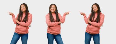 Sürpriz bir şey gri arka plan üzerinde sunulması gülümseyen fitness genç siyah kadın tarafına işaret kümesi