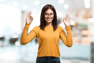 Neşeli ve heyecanlı ve çığlık, onay ve bir kafeterya başarı kavramı ok jest yapıyor kendine güvenen genç güzel kadın