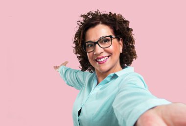 Gülümseyen kadın orta yaşlı ve mutlu, kamerayı, bir selfie alarak onun tatil veya önemli bir olay, neşeli ifade heyecanlı