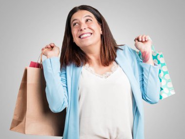 Orta yaşlı kadın neşeli ve gülümseyen, alışveriş çantaları taşırken çok heyecanlı alışverişe gitmek ve yeni tekliflere bak hazır