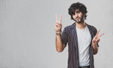 Genç yakışıklı adam eğlenceli ve mutlu, pozitif ve doğal, zafer, barış kavramı bir jest yapar