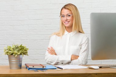 Kollarını, gülümseyen ve mutlu crossing, kendinden emin ve dostça görevleri yapmak onun masasına oturan genç öğrenci portresi