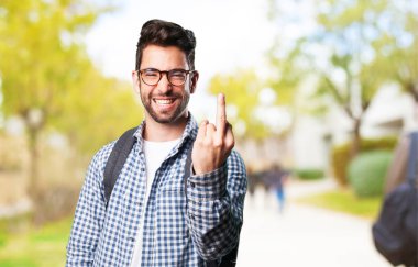 Genç adam hakaret ile orta parmak üzerinde arka plan bulanık