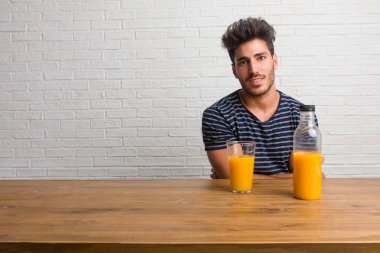Kollarını, gülümseyen ve mutlu crossing, kendinden emin ve dostu bir masada oturan genç yakışıklı ve doğal adam. Bir kahvaltı yapıyor, portakal suyu ve tahıl bowl içerir.
