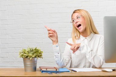 Tarafına işaret görevleri yapmak masasına oturan genç öğrenci portresi, gülümseyen bir şey, doğal ve rahat sunan şaşırttı