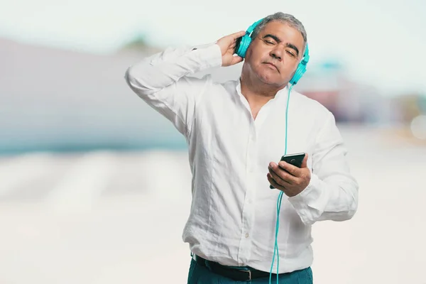 Middle aged man relaxed and concentrated, listening to music with his mobile phone