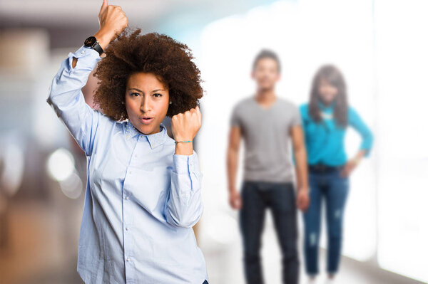 young black woman doing winner gesture with blurred people in background