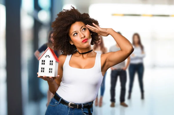 Молода Чорна Жінка Тримає Модель Маленького Будинку Розмитими Людьми Задньому — стокове фото
