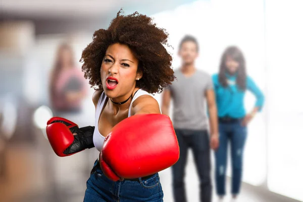 young black woman using boxing gloves with blurred people in background