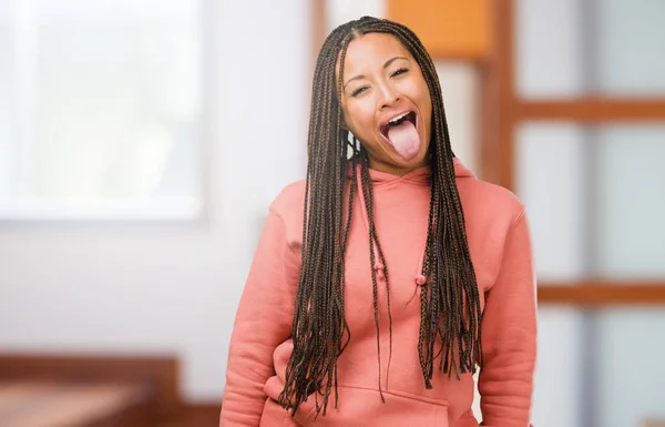 Portrait of a young black woman wearing braids expression of confidence and emotion, fun and friendly, showing tongue as a sign of play or fun