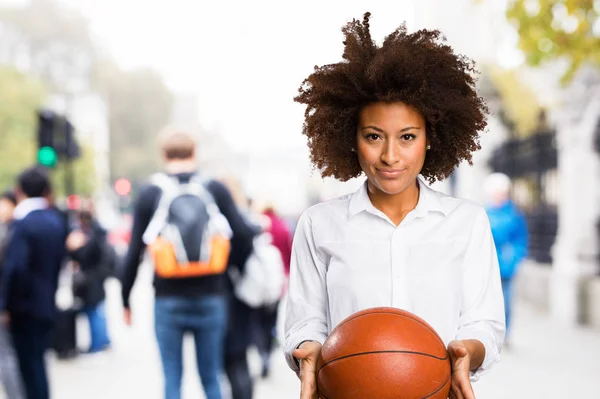 young black woman holding a basket ball on blurred background