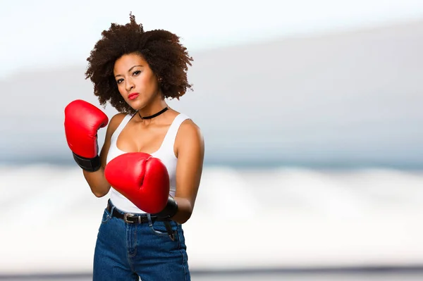 young black woman using boxing gloves on blurred background