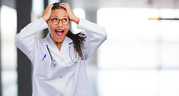 Portrait of a young black doctor woman frustrated and desperate, angry and sad with hands on head