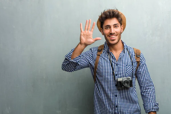 年轻英俊的旅行者男子戴着草帽 背包和显示5号的照相机 象征着数数 数学的概念 自信和开朗 — 图库照片