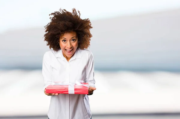 young black woman holding a gift on blurred background
