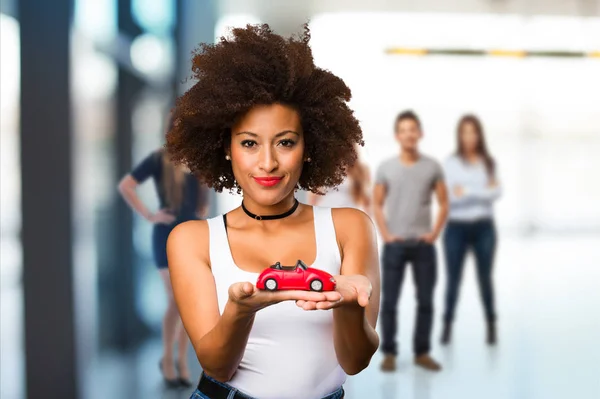 Young Black Woman Holding Red Car Model Blurred People Background — Stock Photo, Image