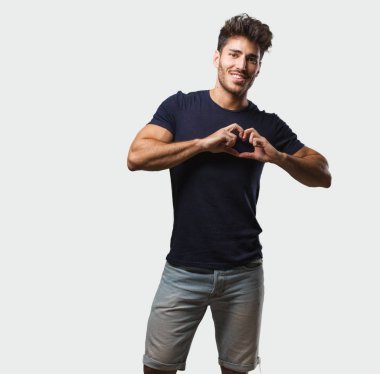 Sevgi ve dostluk, mutlu ve gülümseyerek kavramı ifade bir kalp el ile yapma ayakta genç yakışıklı adam