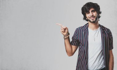 Sürpriz bir şey, doğal ve rahat sunan gülümseyen genç yakışıklı adam tarafına işaret