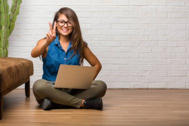 Gösterilen iki numaralı sayma simgesi, matematik, kendinden emin ve neşeli kavramı katta oturan genç latin kadın portresi. Bir dizüstü bilgisayar holding.