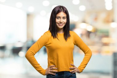 Kalça, rahat ve gülümseyen, çok olumlu ve neşeli bir kafeteryada ayakta eller genç güzel kadın