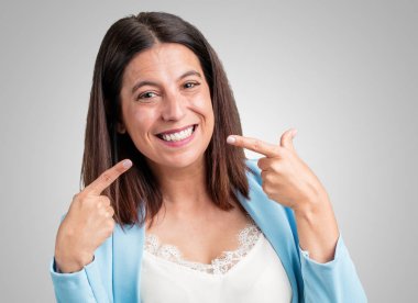 Orta yaşlı kadın gülümsüyor, işaretleme ağız, mükemmel dişleri kavramı, beyaz dişler, neşeli ve neşeli bir tutum var.